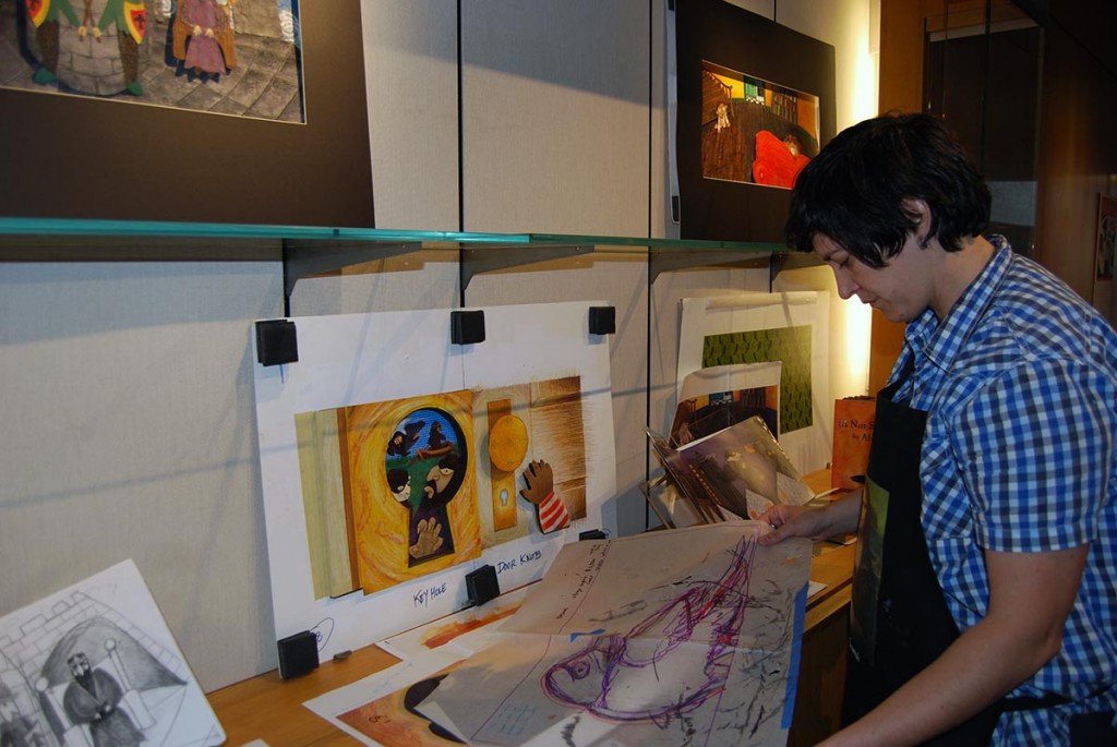 Professor Alison Paul installs her exhibit featuring art from her children's book "The Crow."