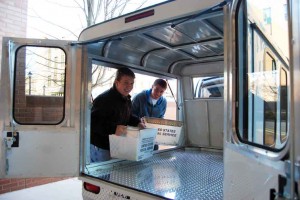 Student workers load books into the new vehicle for delivery on campus.